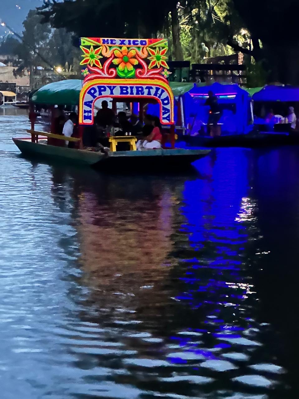 Trajinera iluminada durante una lunada en el canal